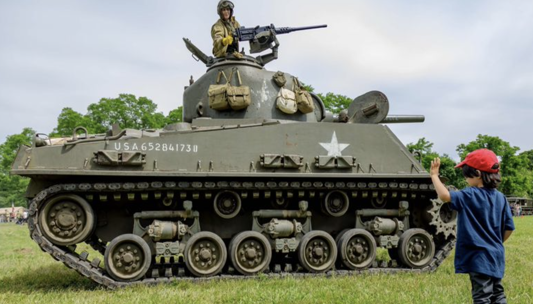 A young museum visitor Is Introduced to The Armor Museum’s Real, Live Sherman and sits in it behind the artillery gun