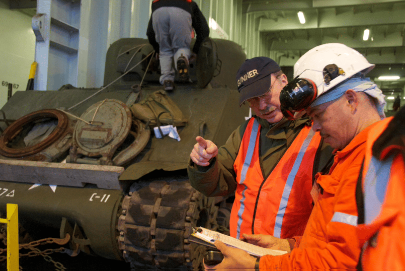 Museum workers looking at details while receiving Sherman tank