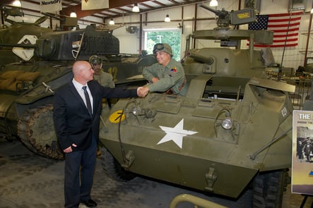 Fred Daum greets driver of tank in Museum of American Armor warehouse