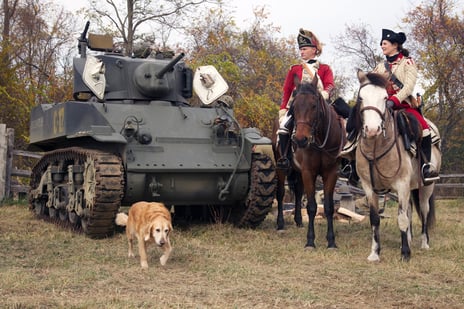 Military Timeline Event with Riders on Horseback with tank and a dog leading the way.